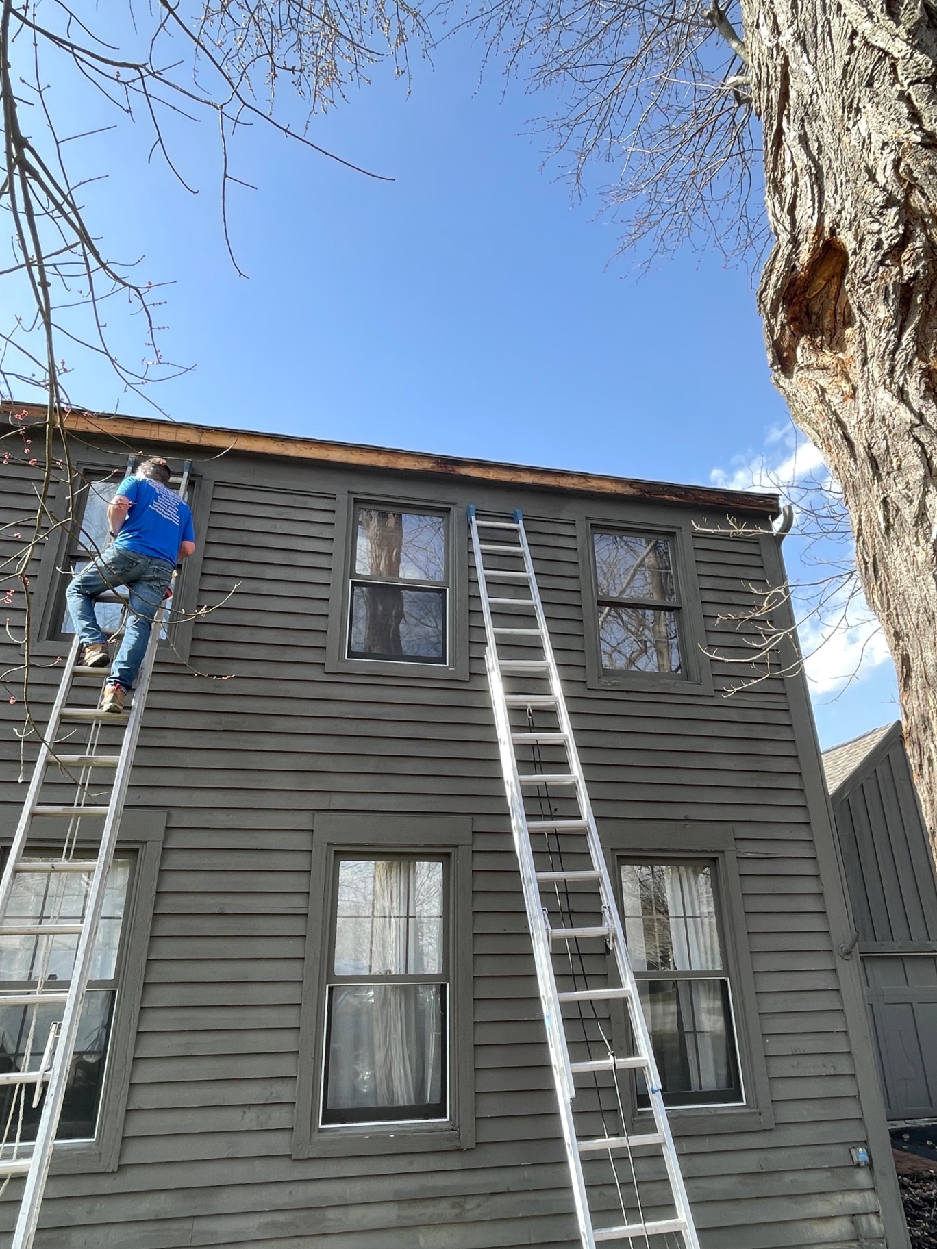 Crew replacing fascia board along the eave of a two-story home